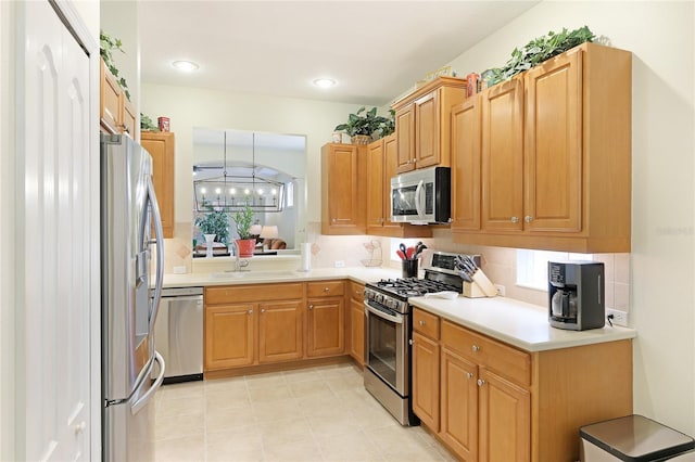 kitchen featuring a sink, stainless steel appliances, backsplash, and light countertops