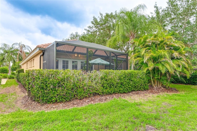 back of property featuring glass enclosure, a yard, and a tiled roof