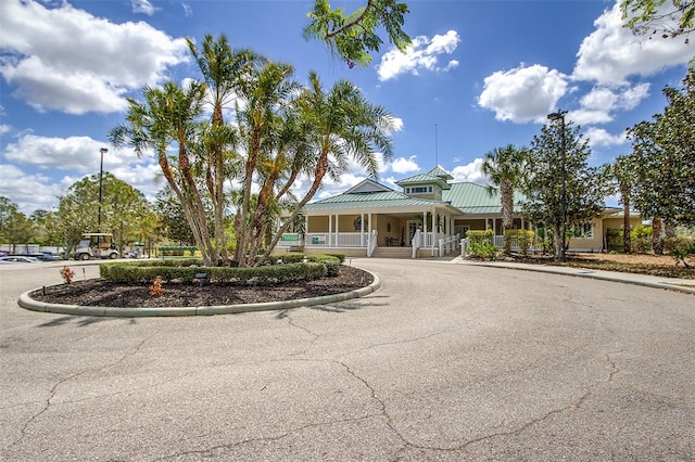 view of front facade with aphalt driveway, a porch, metal roof, and a standing seam roof