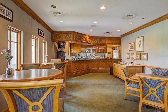 kitchen featuring visible vents, brown cabinets, light colored carpet, and crown molding