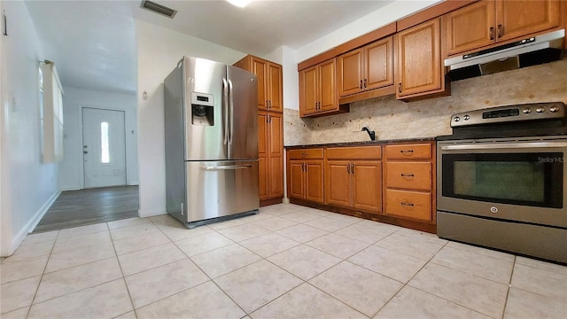 kitchen featuring under cabinet range hood, visible vents, stainless steel appliances, and brown cabinetry