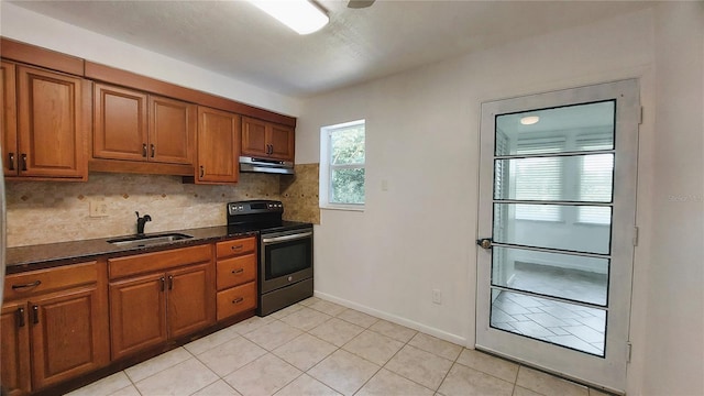 kitchen with under cabinet range hood, brown cabinetry, backsplash, and stainless steel range with electric cooktop