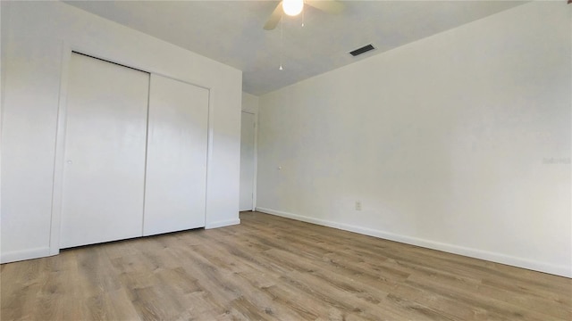 unfurnished bedroom featuring baseboards, visible vents, ceiling fan, light wood-style floors, and a closet