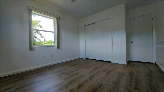 unfurnished bedroom with a closet, baseboards, and wood finished floors