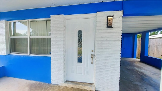 property entrance with brick siding and fence