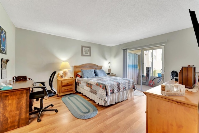 bedroom featuring access to exterior, light wood-style flooring, and a textured ceiling