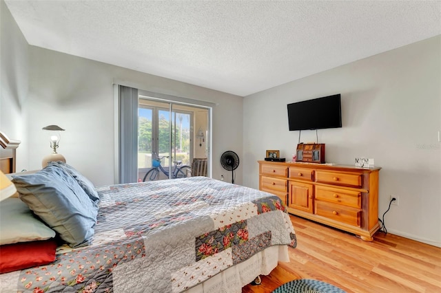 bedroom featuring light wood-style floors, access to outside, a textured ceiling, and baseboards