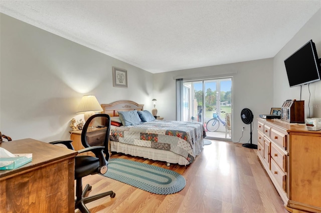 bedroom with light wood-type flooring, access to outside, and a textured ceiling