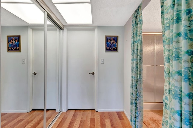 interior space featuring a textured ceiling, light wood-type flooring, and baseboards