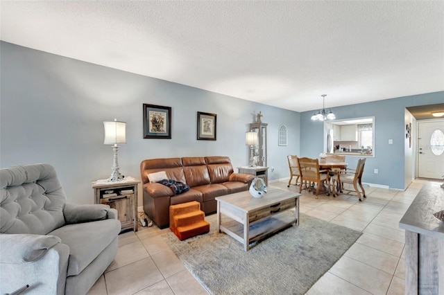 living area featuring light tile patterned flooring, a notable chandelier, a textured ceiling, and baseboards