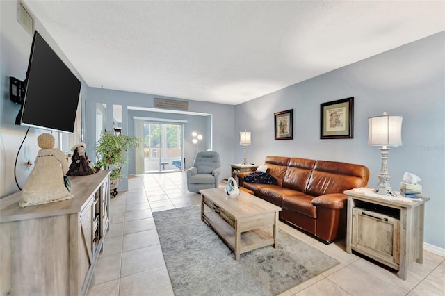 living area with light tile patterned floors, baseboards, visible vents, and a textured ceiling