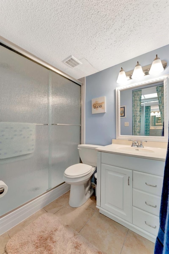 bathroom with a stall shower, visible vents, toilet, tile patterned floors, and vanity