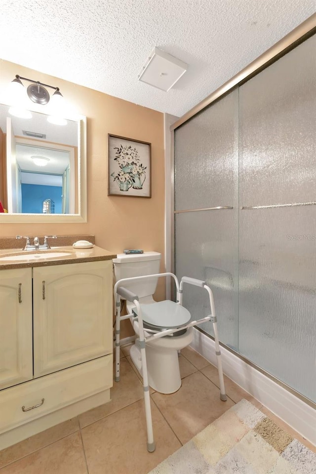 full bathroom featuring toilet, vanity, a textured ceiling, and tile patterned floors