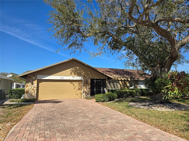 view of front facade featuring a garage, stone siding, and decorative driveway