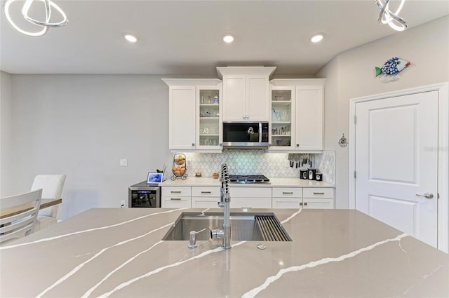 kitchen featuring backsplash, recessed lighting, appliances with stainless steel finishes, white cabinets, and a sink