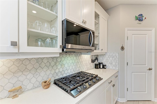 kitchen featuring backsplash, glass insert cabinets, light countertops, white cabinets, and stainless steel appliances