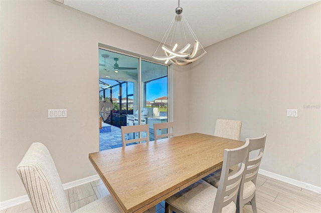 dining room with ceiling fan with notable chandelier and baseboards