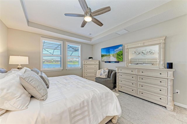 bedroom featuring visible vents, light carpet, a raised ceiling, a ceiling fan, and baseboards