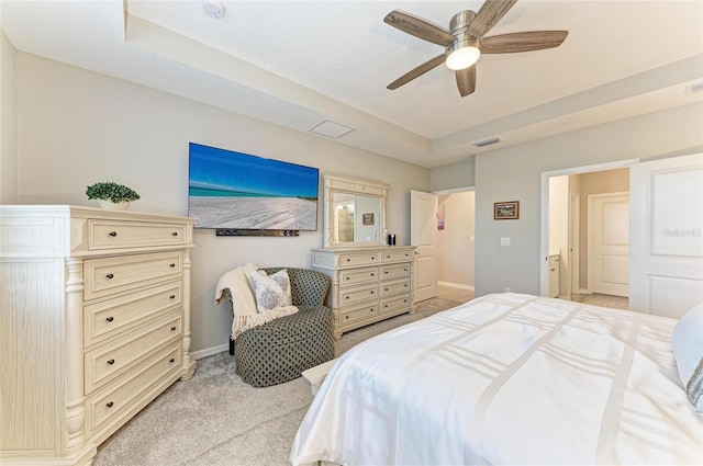 bedroom featuring visible vents, ceiling fan, baseboards, a tray ceiling, and light carpet