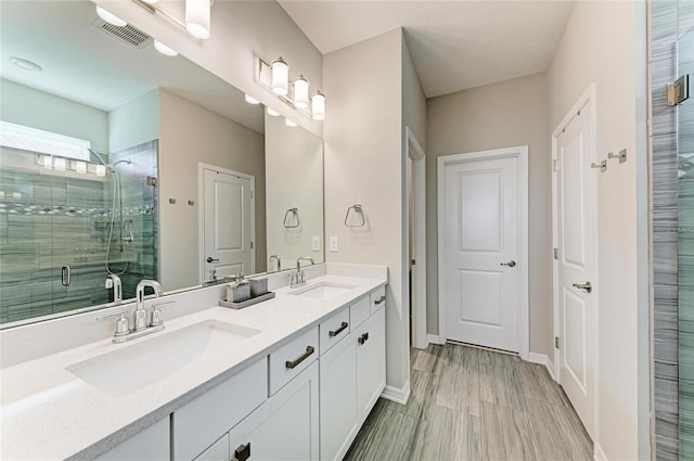 full bath with double vanity, a stall shower, visible vents, and a sink