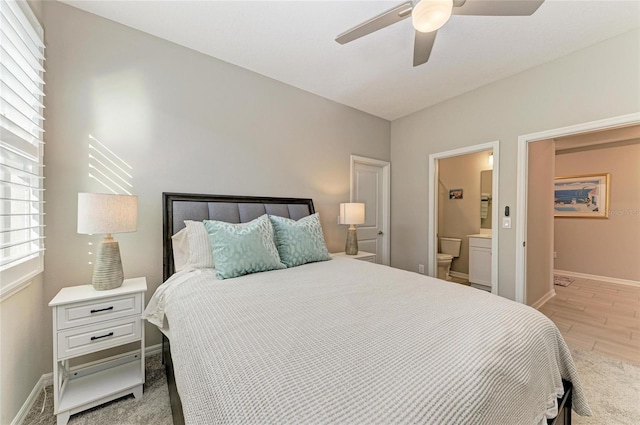 bedroom with ensuite bath, wood finished floors, baseboards, and ceiling fan