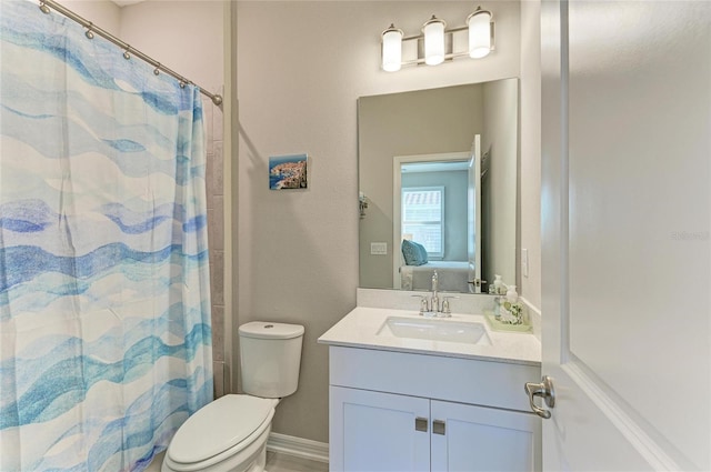 ensuite bathroom featuring vanity, a shower with shower curtain, baseboards, ensuite bath, and toilet