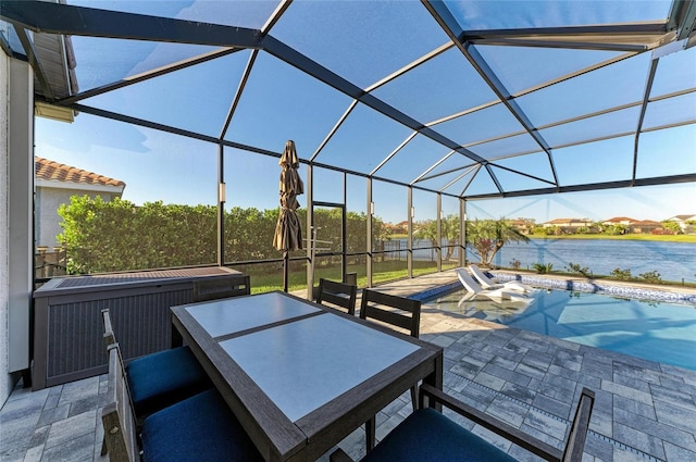 view of patio with outdoor dining space, a lanai, and a water view