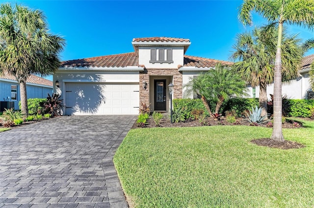 mediterranean / spanish-style home with a front yard, stucco siding, decorative driveway, a garage, and stone siding