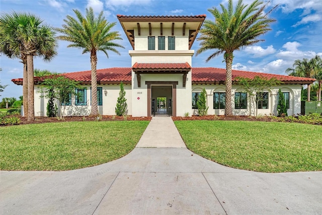 mediterranean / spanish house with stucco siding, a front lawn, and a tiled roof