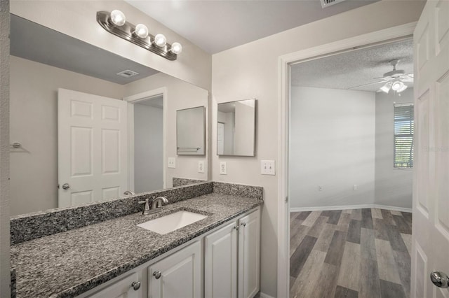 bathroom featuring visible vents, ceiling fan, vanity, wood finished floors, and baseboards