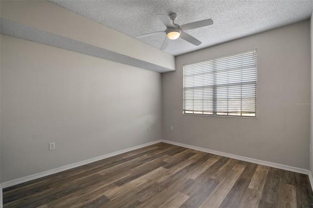 spare room with a textured ceiling, ceiling fan, dark wood finished floors, and baseboards