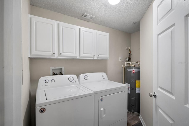 clothes washing area featuring a textured ceiling, washing machine and dryer, electric water heater, visible vents, and cabinet space