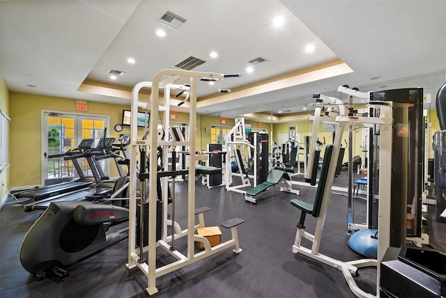 gym with a tray ceiling, visible vents, and recessed lighting