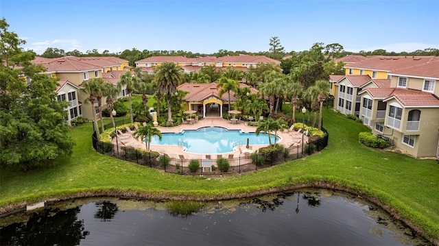 view of pool featuring a yard, a water view, fence, and a residential view