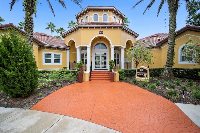 mediterranean / spanish house featuring french doors, a tiled roof, and stucco siding