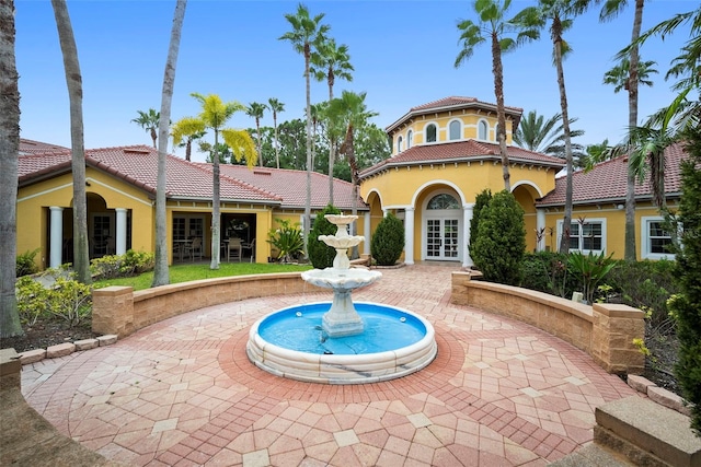 back of property featuring a tiled roof, french doors, a patio area, and stucco siding