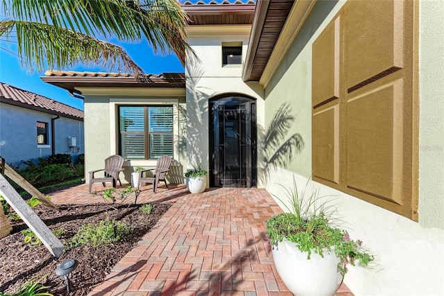 view of exterior entry featuring a patio area and stucco siding