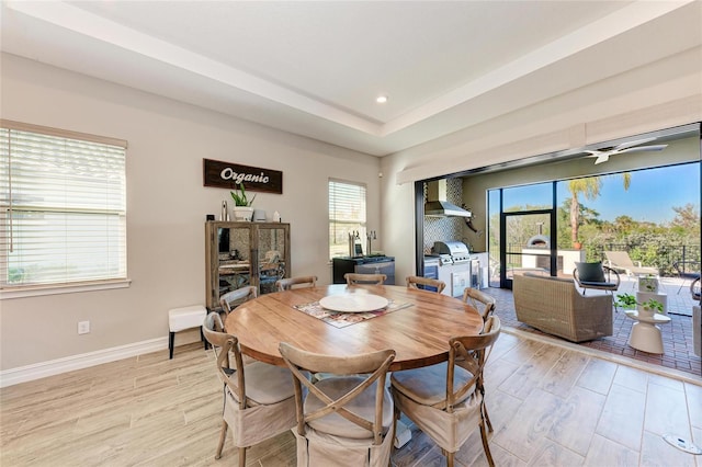 dining area featuring light wood finished floors, baseboards, a raised ceiling, and recessed lighting