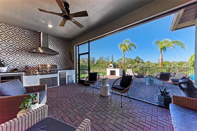 view of patio / terrace featuring a ceiling fan, grilling area, fence, exterior kitchen, and an outdoor living space with a fireplace