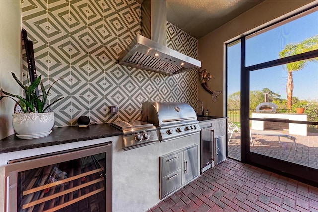 kitchen with refrigerator, dark countertops, a sink, beverage cooler, and wall chimney exhaust hood