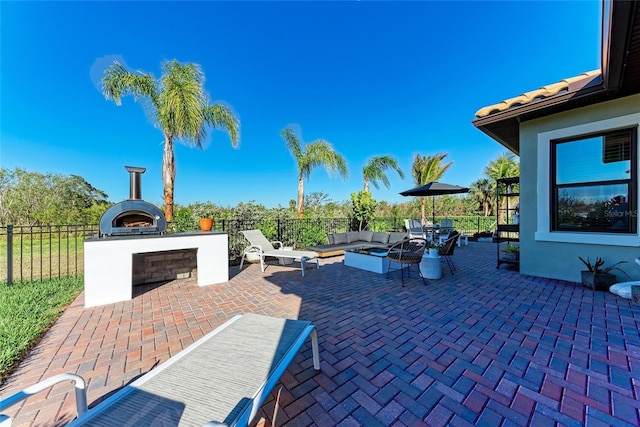 view of patio with an outdoor living space with a fireplace and fence