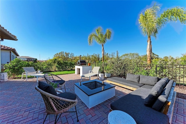 view of patio / terrace with area for grilling, an outdoor living space with a fire pit, an outdoor kitchen, and fence