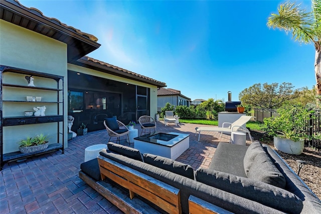 view of patio featuring a sunroom, an outdoor living space with a fire pit, and fence