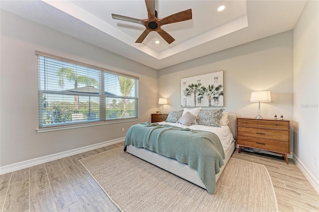 bedroom featuring recessed lighting, a raised ceiling, ceiling fan, light wood-type flooring, and baseboards