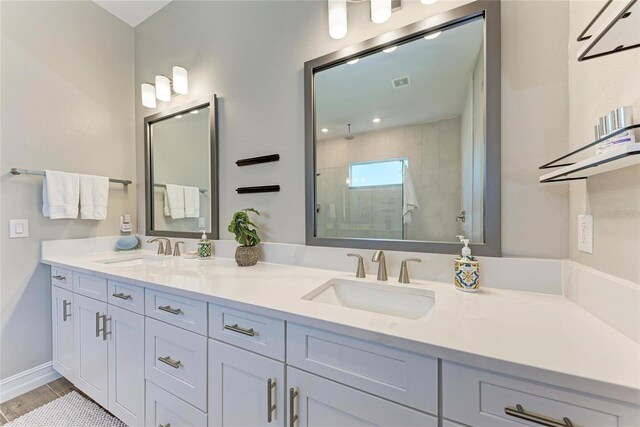 bathroom with double vanity, wood finished floors, a sink, and a shower with door