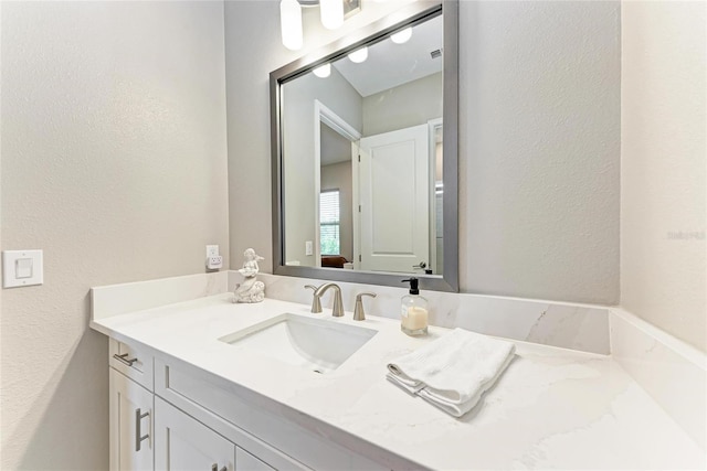 bathroom with a textured wall and vanity