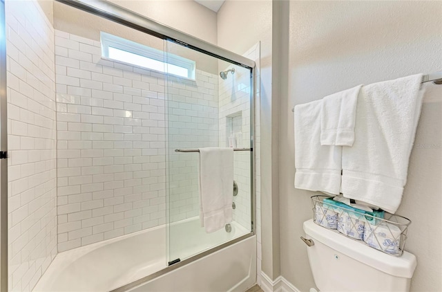 full bath featuring toilet and bath / shower combo with glass door