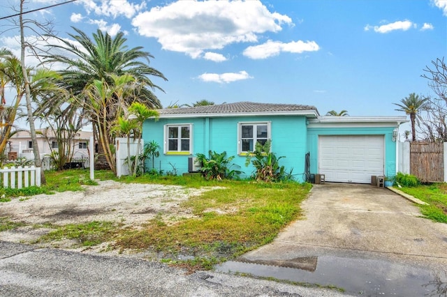 view of front facade with an attached garage, driveway, and fence
