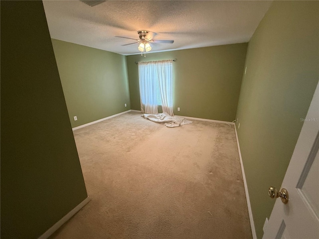 spare room featuring a textured ceiling, carpet, a ceiling fan, and baseboards