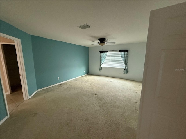 carpeted spare room with ceiling fan, visible vents, and baseboards